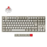 A mechanical keyboard shown on a plain white background, with a separate transparent switch and a red switch keycap displayed above and below the keyboard. The keyboard has a warm light gray/beige body with white keycaps and a single red accent keycap.
